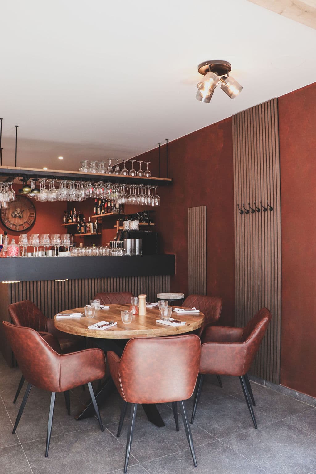 Warm en sfeervol interieur van Vleesrestaurant Martin met ronde tafel, cognackleurige leren stoelen en terracotta muren