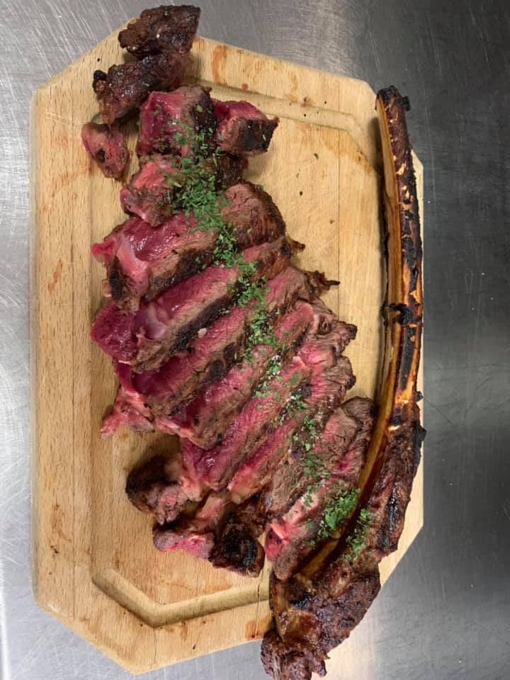 Tomahawk steak gepresenteerd op een houten plank bij Vleesrestaurant Martin